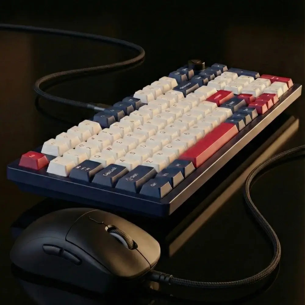 Mechanical keyboard with red and blue keys and a mouse on a dark surface
